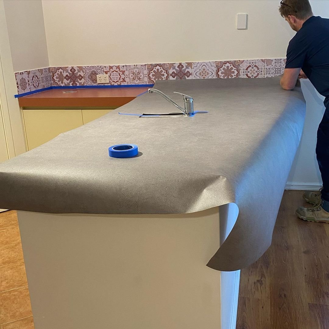 Stone-look vinyl being applied over an existing kitchen benchtop